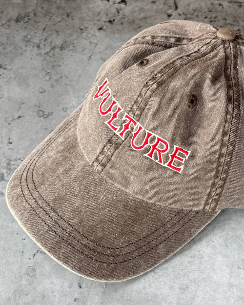 Brown cap with 'Vulture' logo on a gray surface